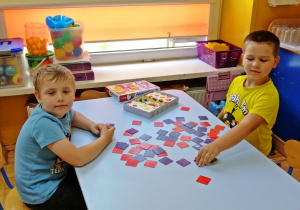 Chłopcy przy stoliku grają w memo obrazkowo-literowe